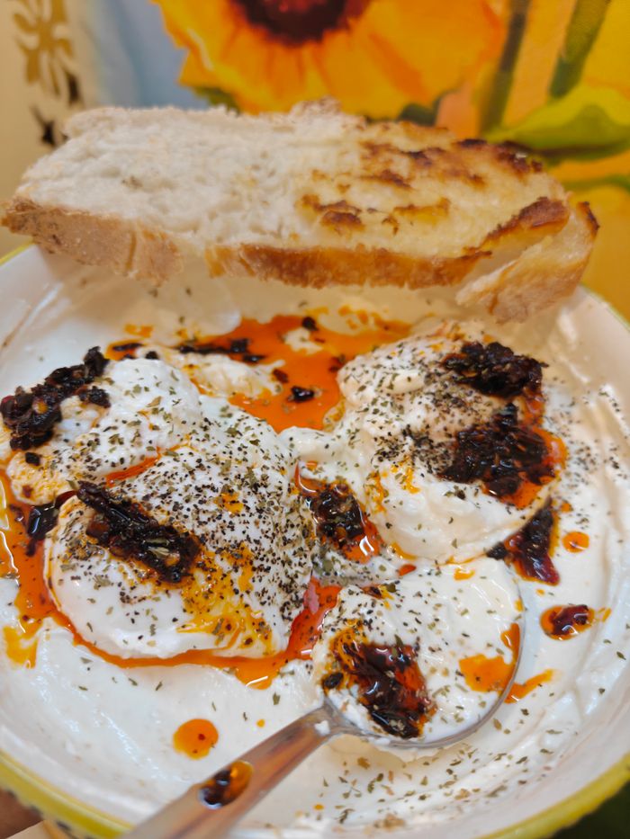 Delicious Turkish poached eggs served with yogurt, chili oil, and fresh bread.